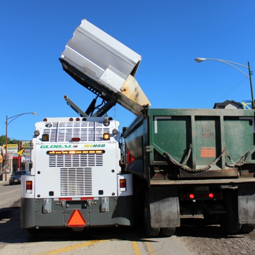 Global Environmental M4HSD Street Sweeper- dumping into milling dump truck rear view